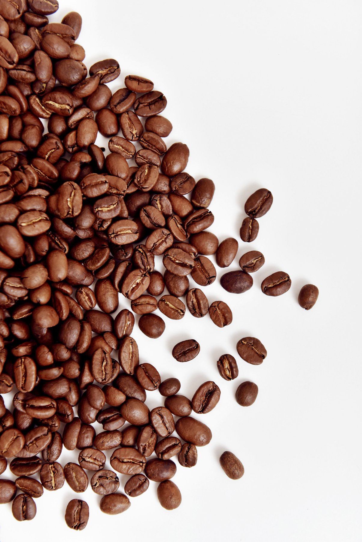 Close-Up Photo of Aromatic Brown Roasted Coffee Beans on White Surface